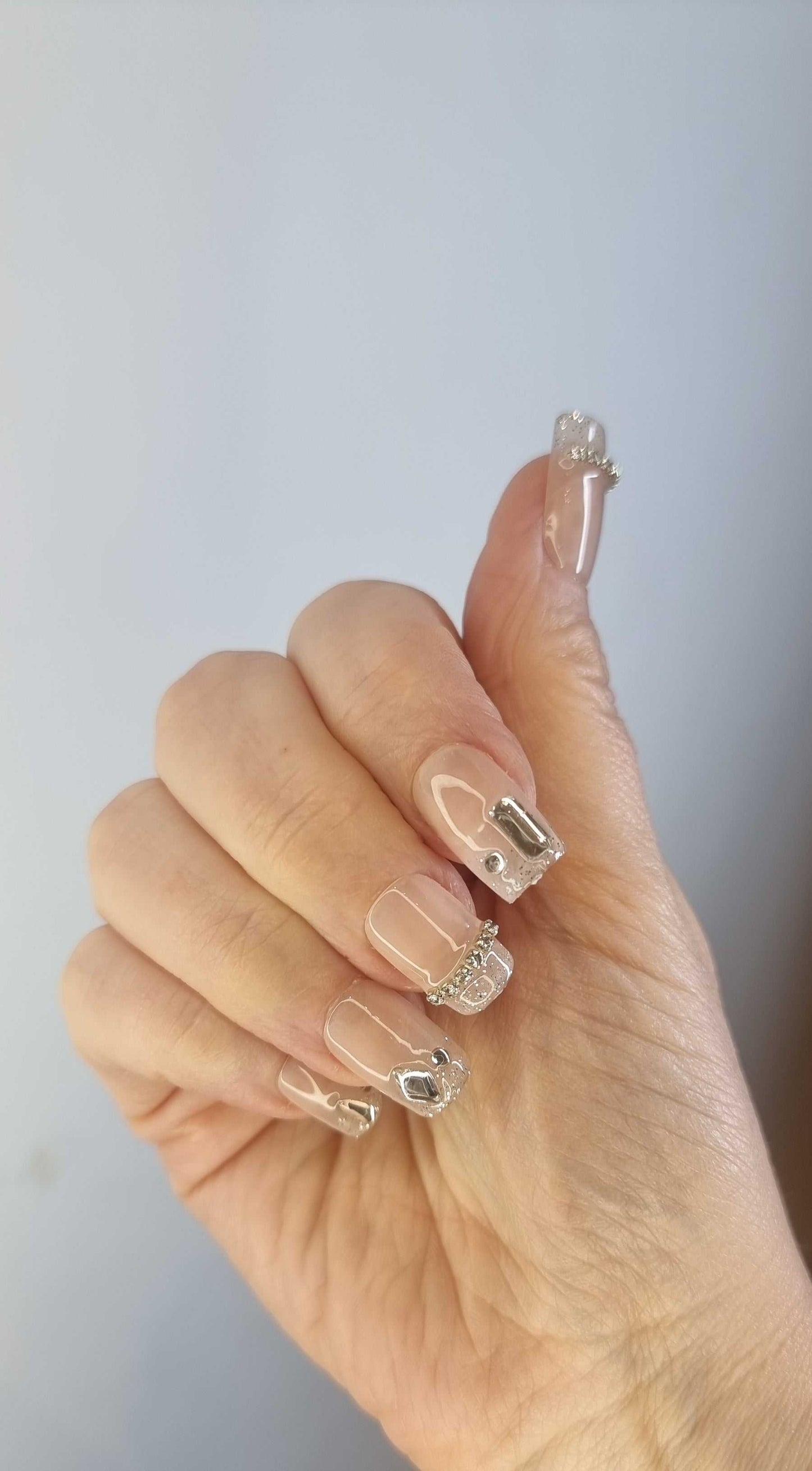 Elegant Ayisa nails with clear polish and silver embellishments for a glamorous look