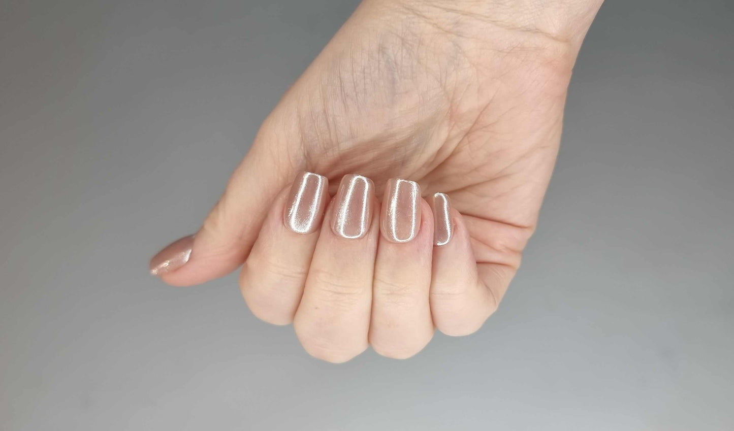 Pearls of Bahrain press-on nails in a short square shape, featuring an elegant, pearlescent champagne shimmer finish, displayed on a textured background.