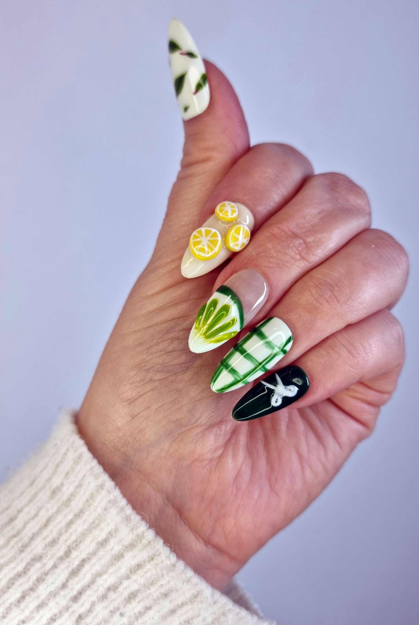 A close-up of the Al Ain Allure manicure, highlighting the detailed, handcrafted 3D citrus art on the long almond press-on nails.