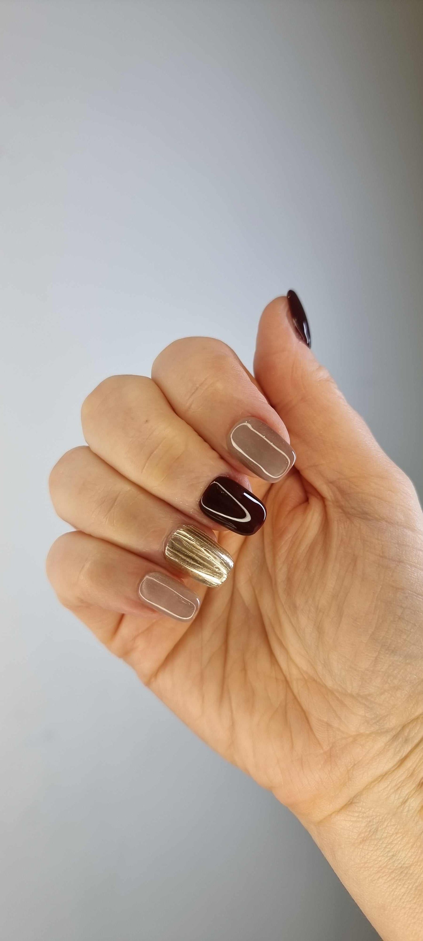 A close-up of the Al Khobar Chic manicure, highlighting the luxurious textured gold accent nail on the short square press-ons.