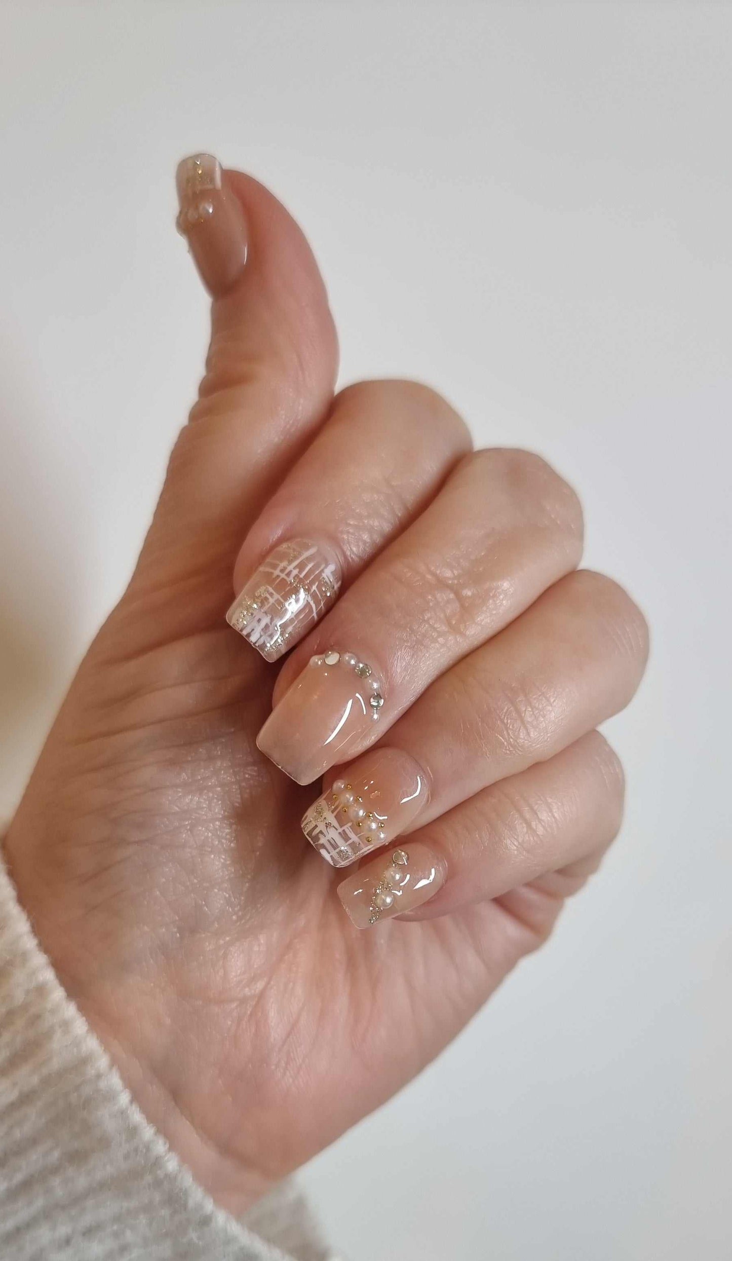 A close-up of the Corniche Chic manicure, highlighting the sophisticated pearl details on the short square press-on nails.