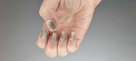 A model's hand wearing the elegant Dammam Delight press-on nails, showcasing the soft cat-eye shimmer.