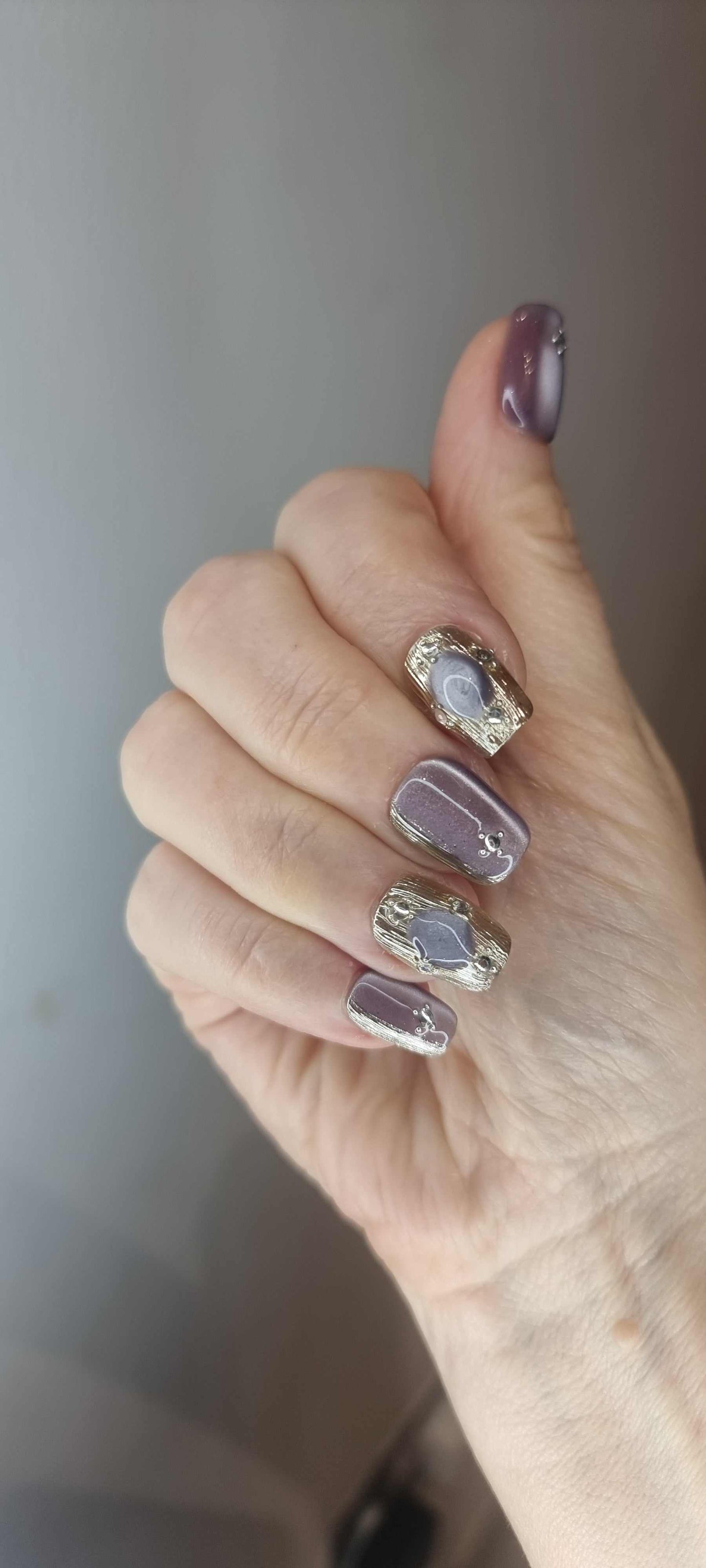 A model's hand wearing the chic Diriyah Elegance press-on nails, showcasing the unique 3D droplet effect.