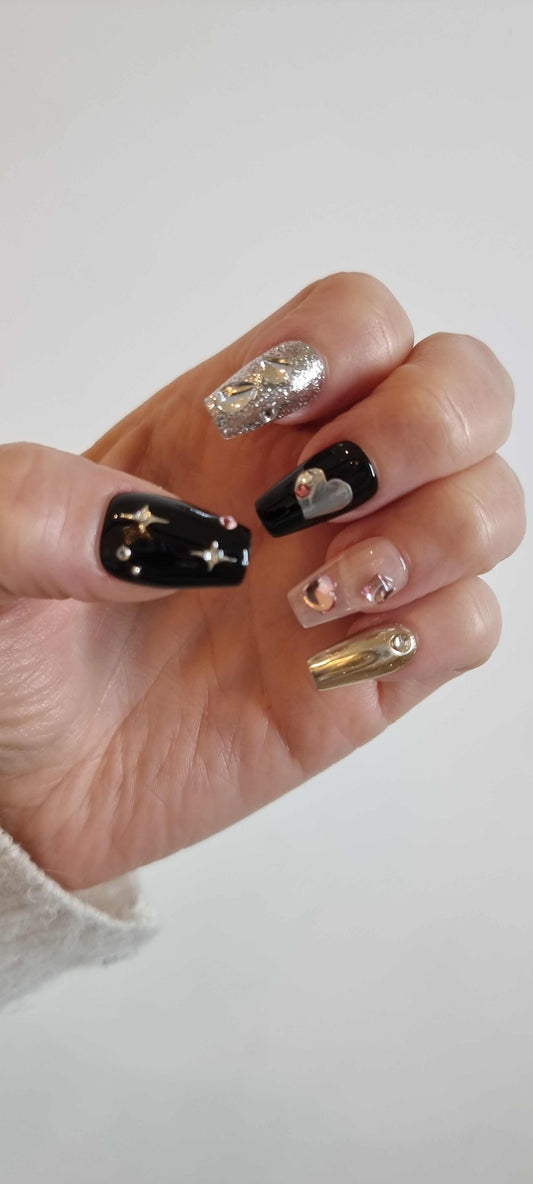 A model's hand showcasing the luxurious Doha Dreams press-on nails, with a focus on the 3D chrome and black nail art.