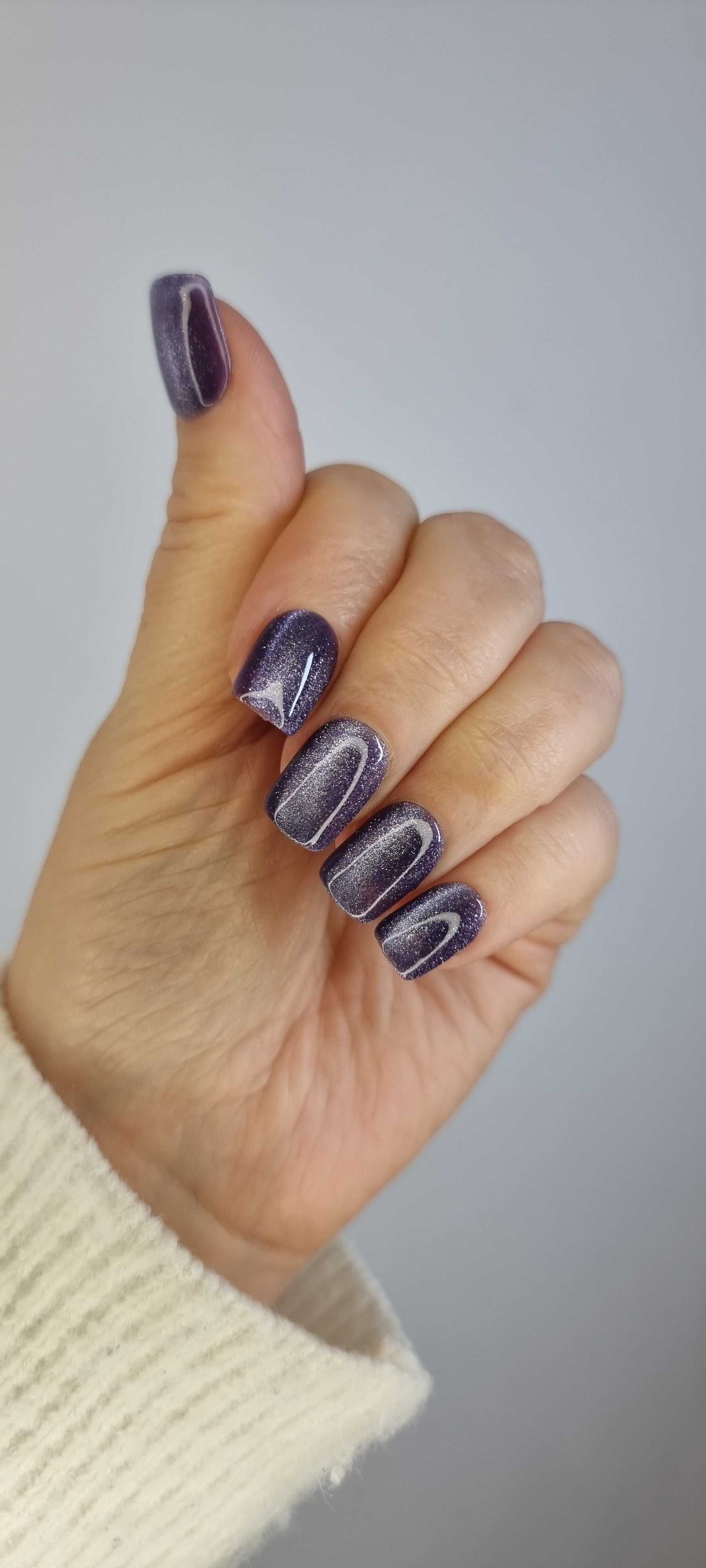 Hand wearing Indigo Rain press-on nails by Nail Addict, showcasing the short square shape and glossy, shimmering indigo color