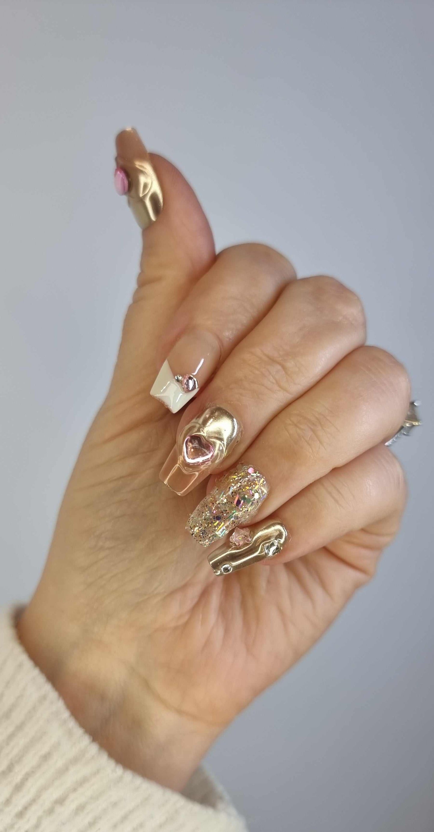Hand wearing Jawhara Glow press-on nails by Nail Addict, showcasing the long coffin shape and elegant pearl and gold chain embellishments.