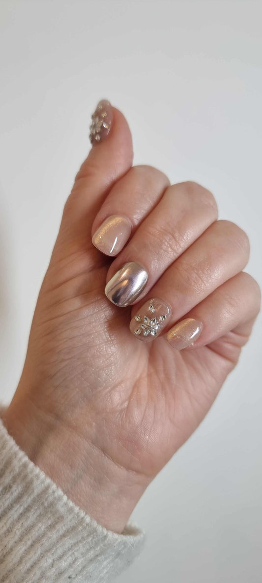 A model's hand wearing the luxurious Liwa Luxe press-on nails, showcasing the intricate 3D gem clusters and chrome finish.