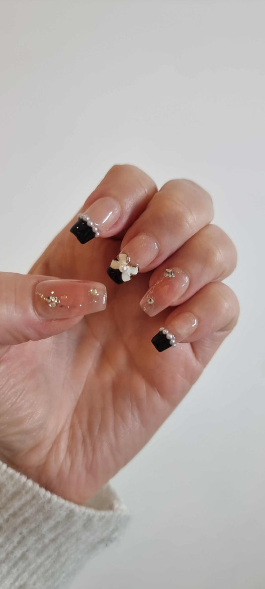 Woman wearing Mecca Magic nude glitter square press-on nails with pearl accents by Nail Addict.