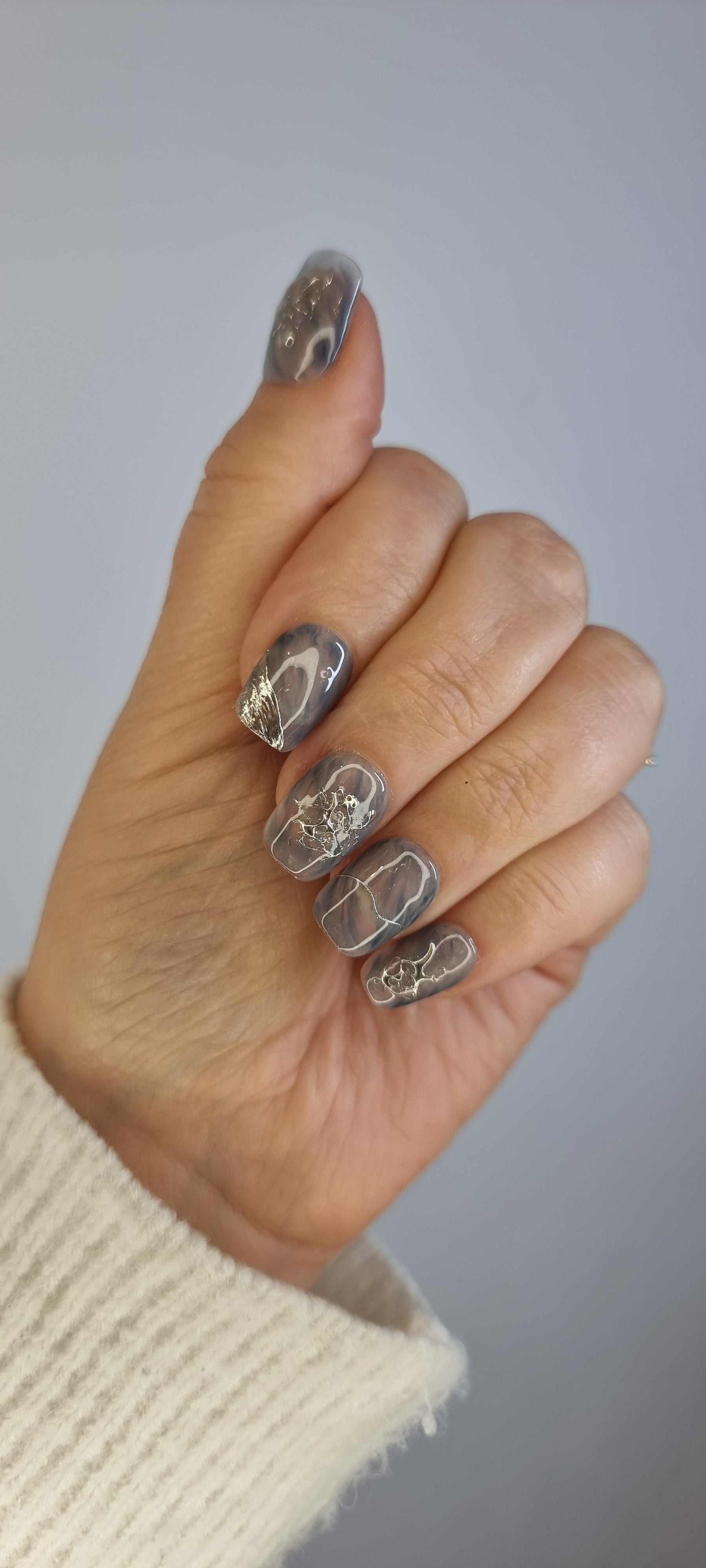 A model's hand wearing the Shaden press-on nails, showcasing a translucent design.