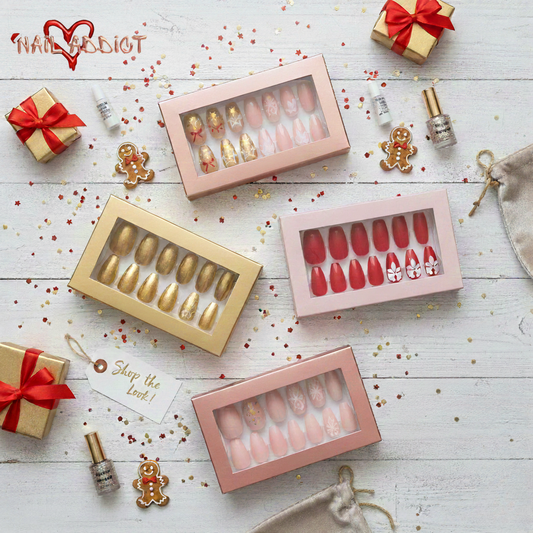 press-on nail sets in gold, gingerbread, and red holiday designs, surrounded by festive gifts, cookies, and glitter on white wood.