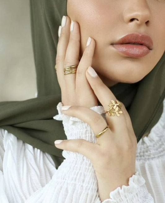 Neutral nude press-on nails on hands, glossy almond shape, elegant Ramadan/Eid beauty look with gold rings and modest styling UAE