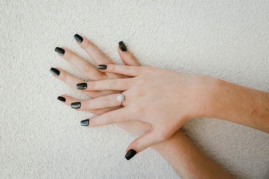 A woman's hands with a flawless, classic black press-on manicure, showcasing a safe and non-damaging alternative to acrylic nails.