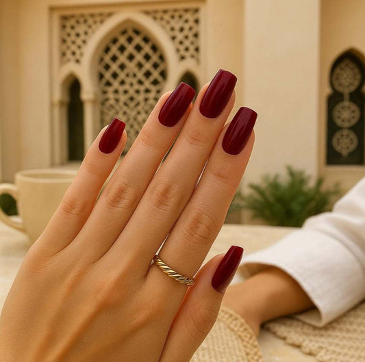 A woman's hand with an elegant red press-on manicure, showcasing a beautiful and Wudu-friendly nail option for Muslim women in the UAE.