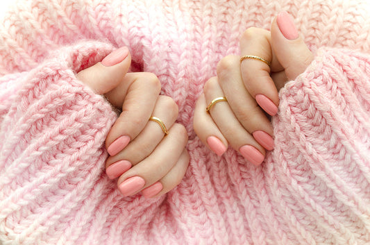 A woman's hands with a healthy, beautiful pink press-on manicure, representing a safe and non-damaging solution for those with nail allergies.