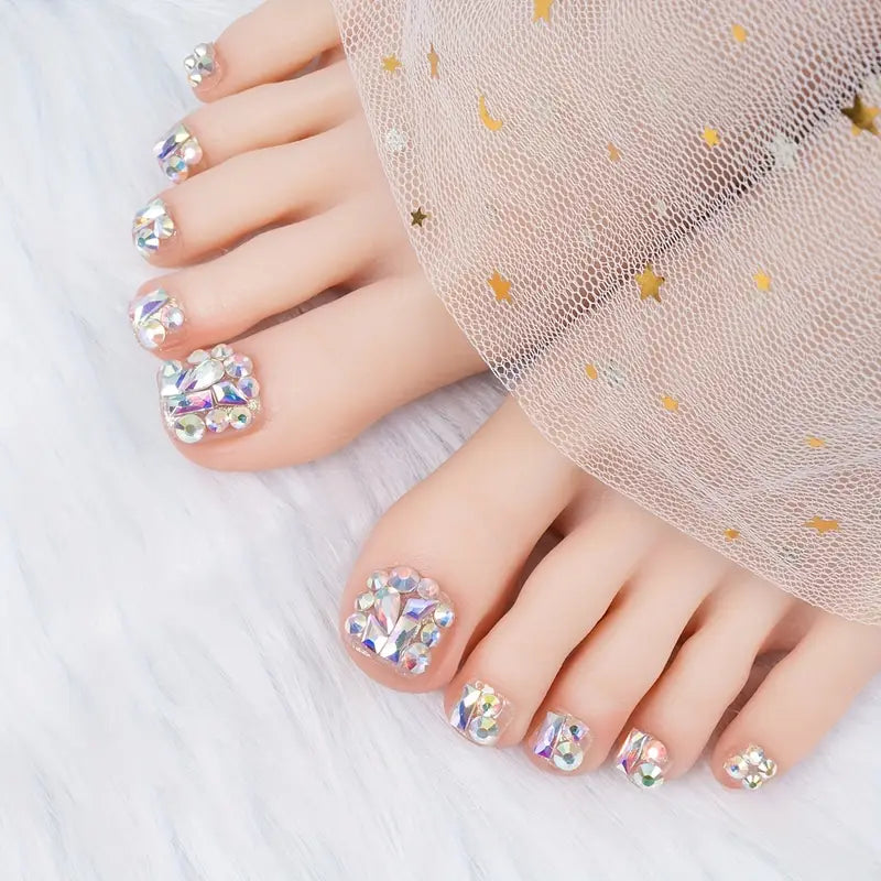 A woman's feet with a glamorous, rhinestone-covered press-on toe nail pedicure, representing the best luxury press-on toenails available in Dubai.