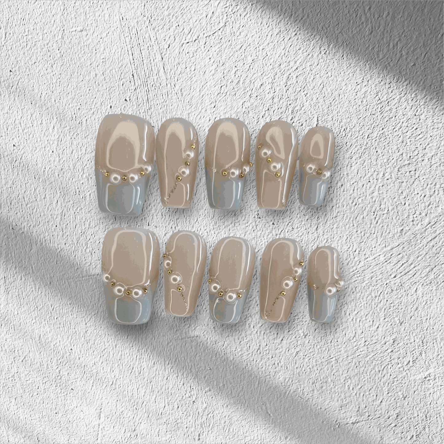 The Fadwa press-on nail set in a medium square shape, featuring a nude base with a modern blue French tip and pearl details.