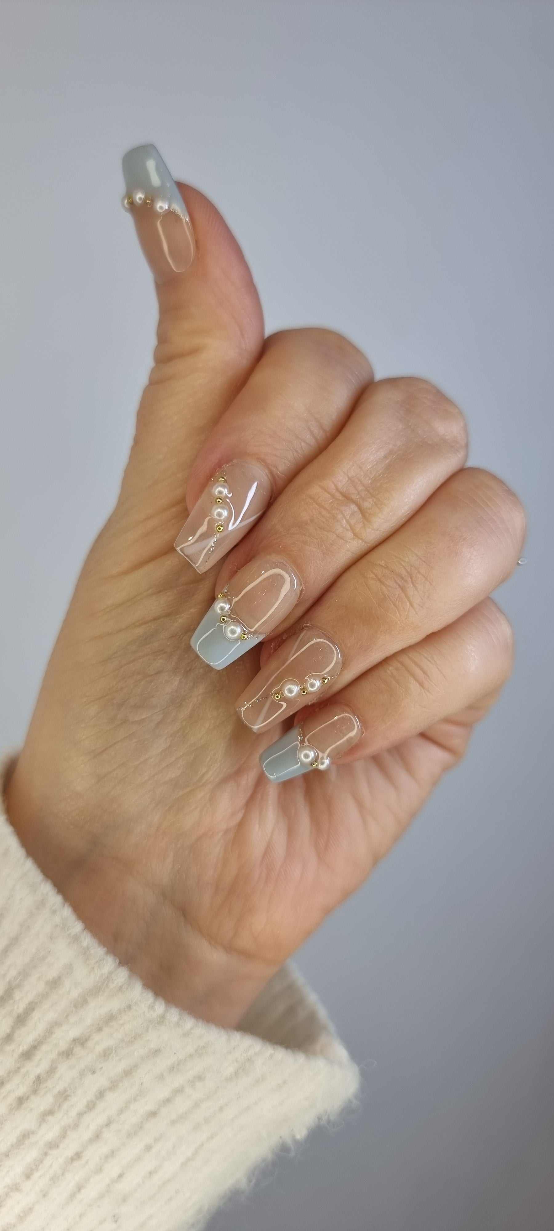 A close-up of the Fadwa manicure, highlighting the unique blue French tip and sophisticated pearl design on the square press-on nails.