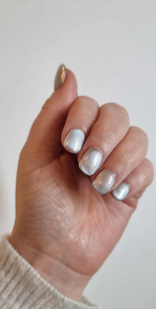 Hand wearing Lujain pearlescent gray-silver short oval press-on nails by Nail Addict, showing the light reflecting off the pearlescent surface.
