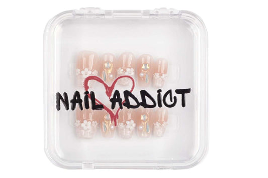 Selina sheer pink and white short square press-on nails by Nail Addict, with a heart charm accent.