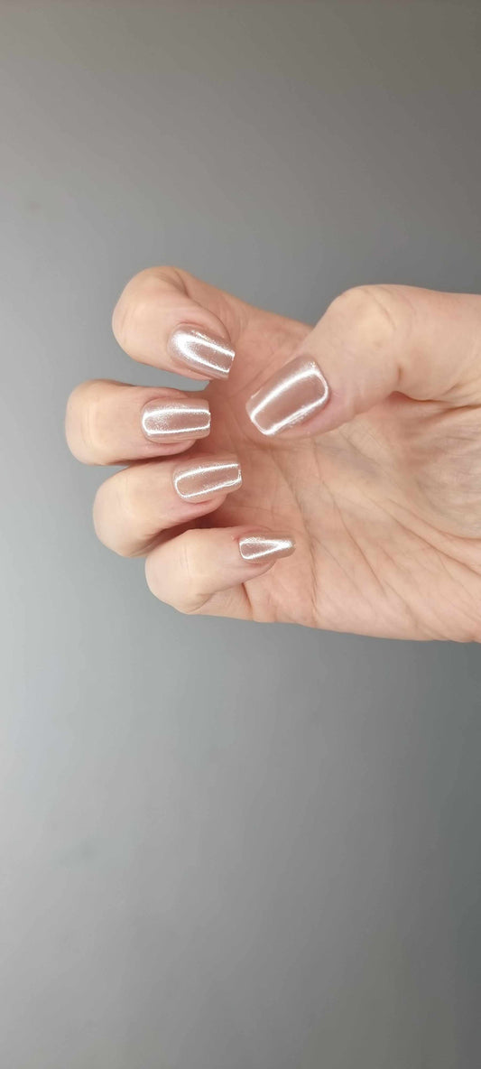 Pearls of Bahrain press-on nails in a short square shape, featuring an elegant, pearlescent champagne shimmer finish, displayed on a textured background.
