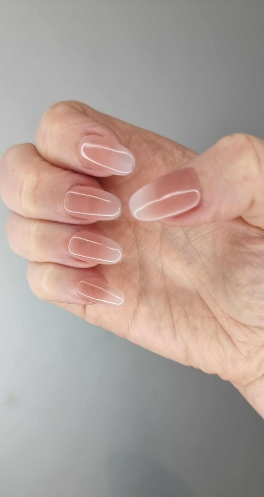 A model's hand wearing the elegant Raneem ombre French tip press-on nails, showcasing the seamless color blend.