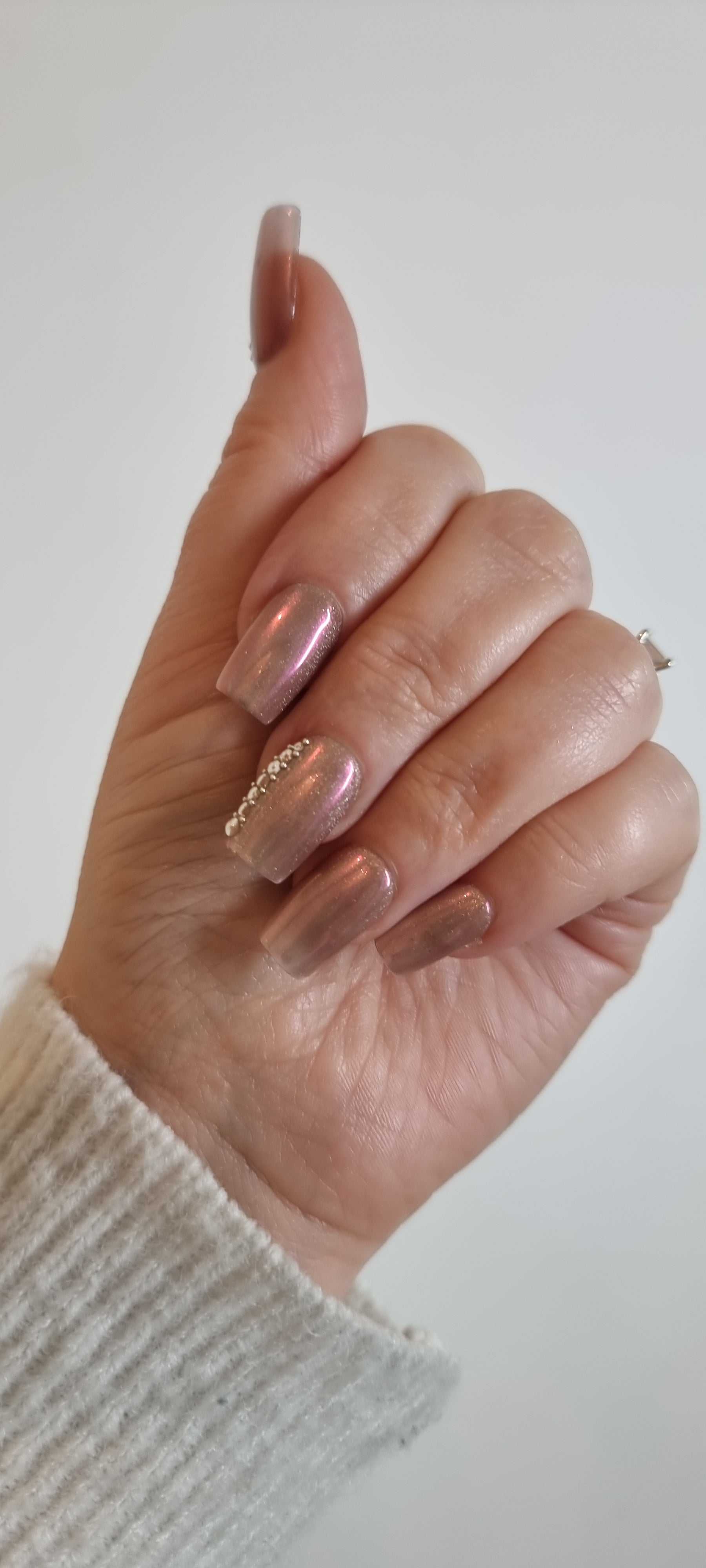 A set of false press-on nails in a sheer, glossy nude color. Each nail is decorated with a vertical line of alternating small white pearls and clear rhinestones.