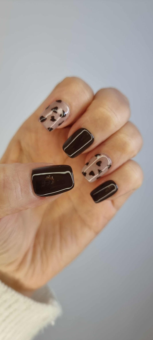 Hand wearing Samira short square press-on nails in a nude shade with a glossy finish and silver chrome accents.