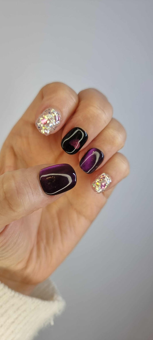 A set of false nails with an abstract design in dark red, black, and white. The design includes a solid black heart on two of the nails.