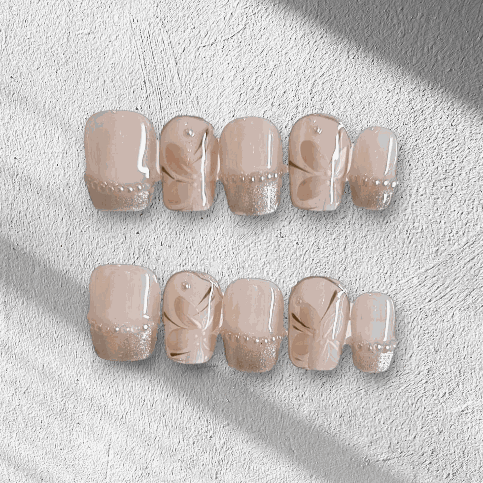 Set of beige and nude artificial nails with floral designs and rhinestone accents for elegant manicure style