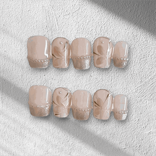 Set of beige and nude artificial nails with floral designs and rhinestone accents for elegant manicure style