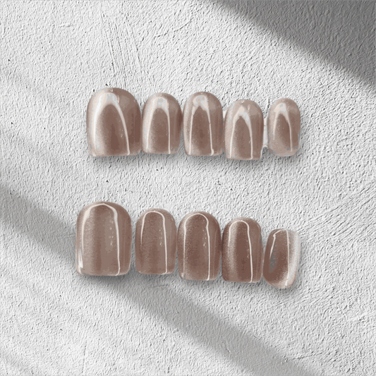 Nude beige glossy press-on false nails set on textured white surface with soft shadow lighting