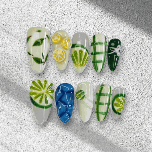 The Al Ain Allure press-on nail set in a long almond shape, featuring intricate 3D citrus and leaf art on a mix of white, green, and blue nails.