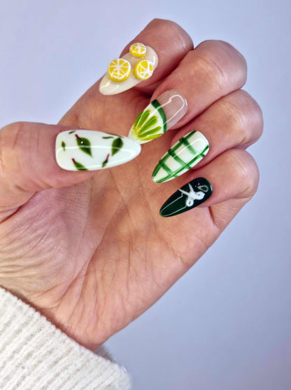A model's hand wearing the vibrant Al Ain Allure press-on nails, showcasing the unique 3D lemon and leaf designs.