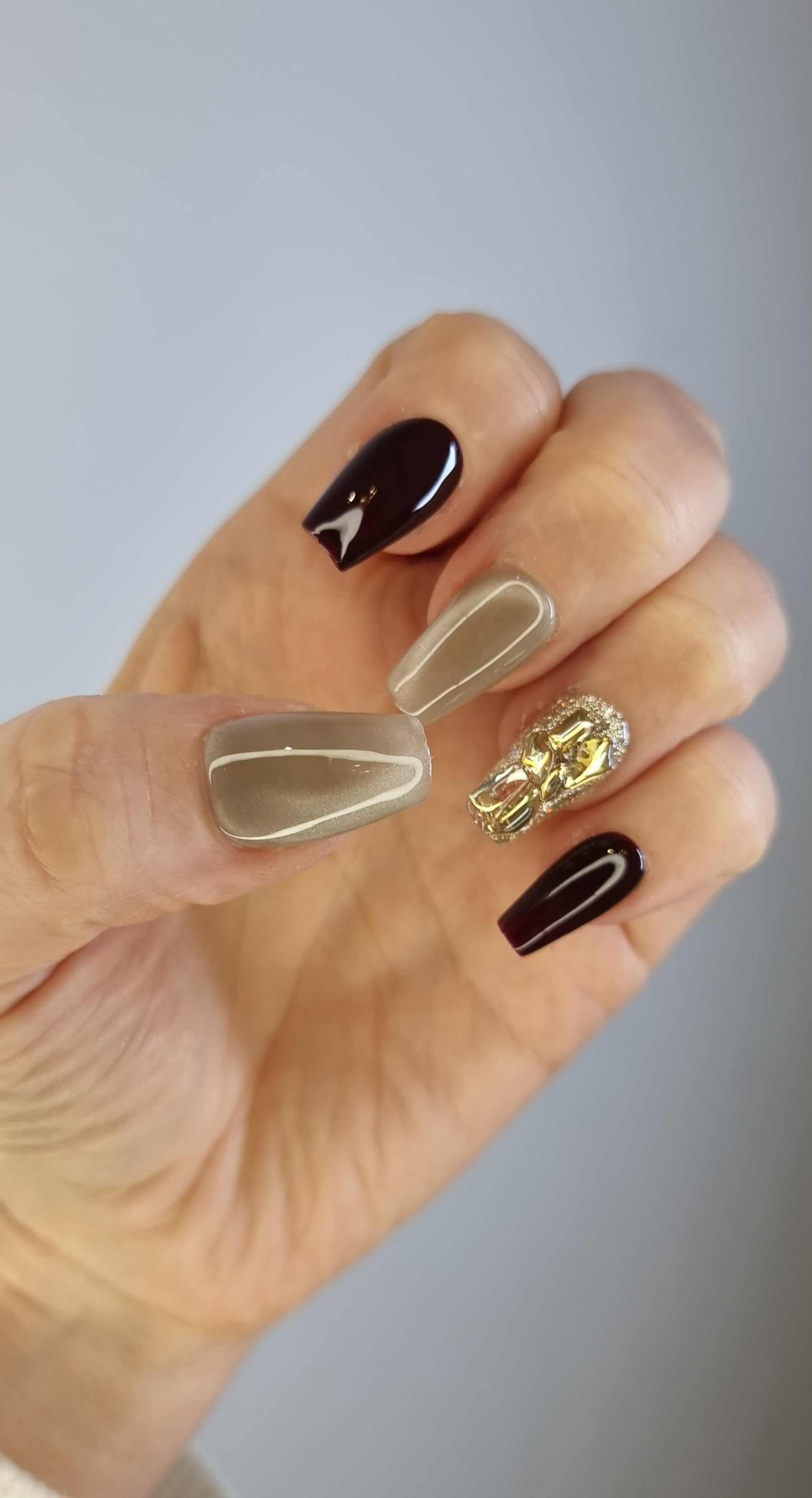 Hand wearing Amani long coffin press-on nails, showcasing the elegant brown and nude tones with subtle heart designs.
