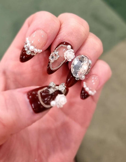 A model's hand wearing the luxurious Abu Dhabi Dazzle press-on nails, showcasing the intricate 3D floral and pearl art.