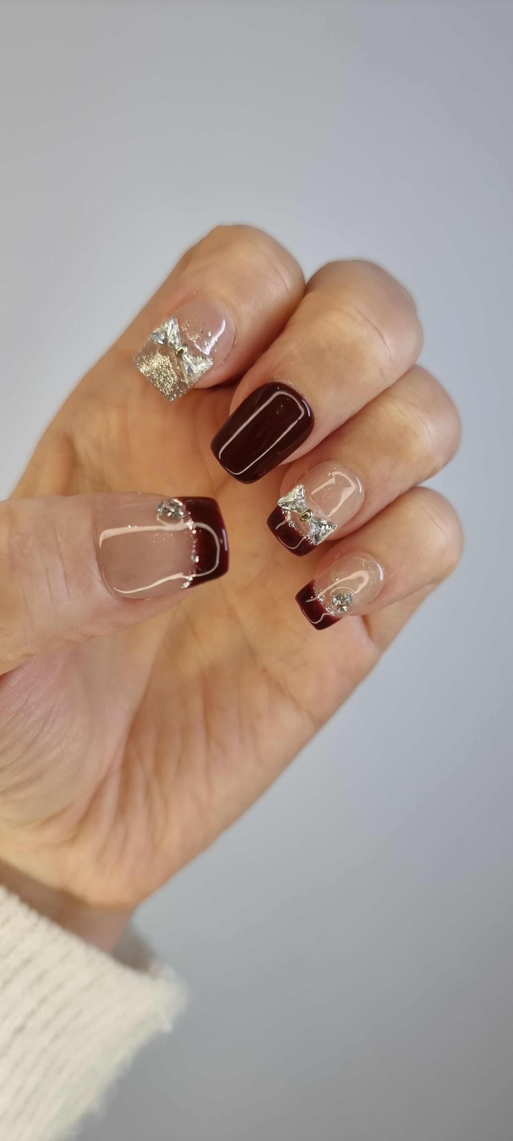 Hand wearing Amira short coffin press-on nails, showcasing the iridescent silver swirls on a glossy pink base.