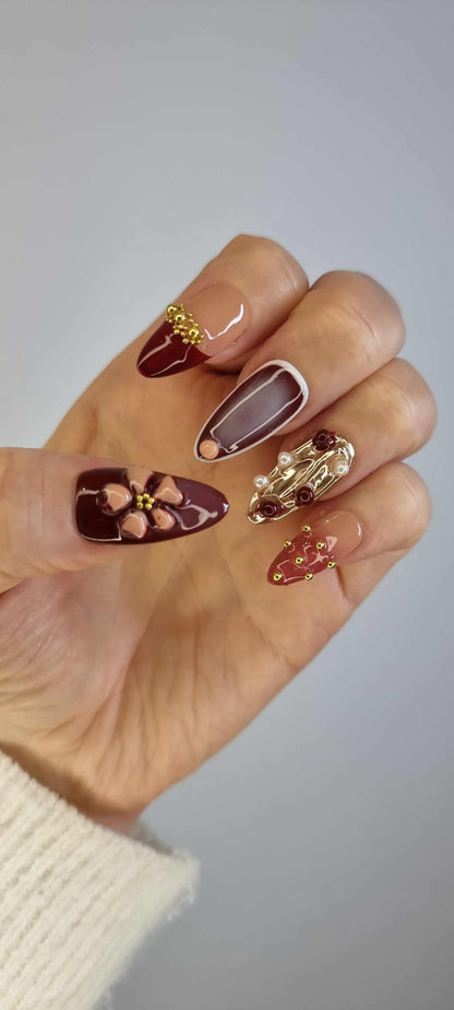 A model's hand wearing the intricate Arabian Nights press-on nails, showcasing the detailed 3D floral art and rich color palette.