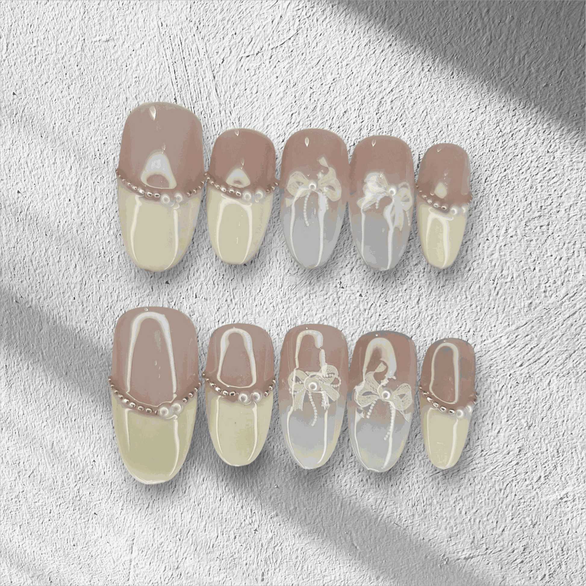 The Aseel press-on nail set in a medium round shape, featuring a classic French manicure design with 3D white bows and pearl details.