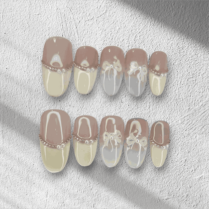 The Aseel press-on nail set in a medium round shape, featuring a classic French manicure design with 3D white bows and pearl details.