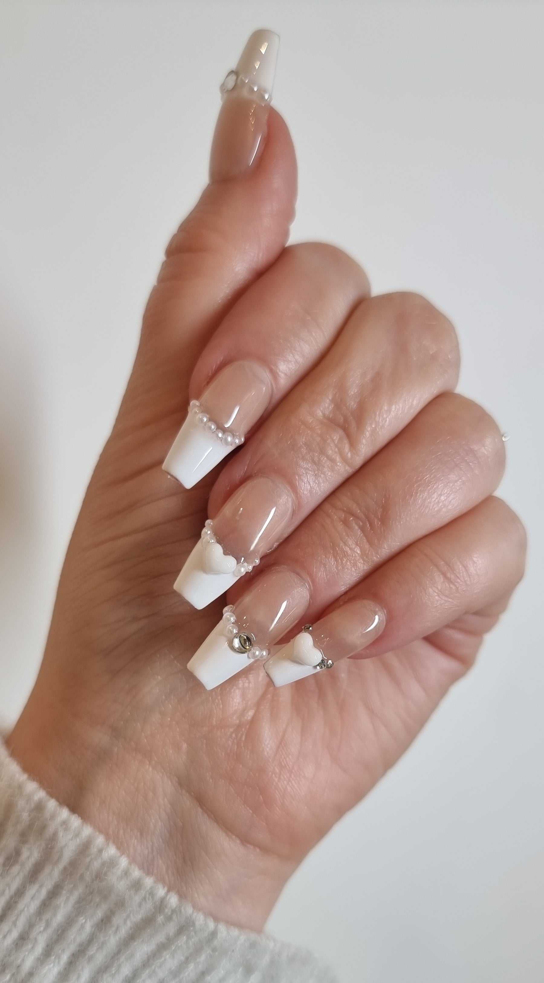 Model's hand wearing the Burj Beauty French manicure press-on nails, side view.