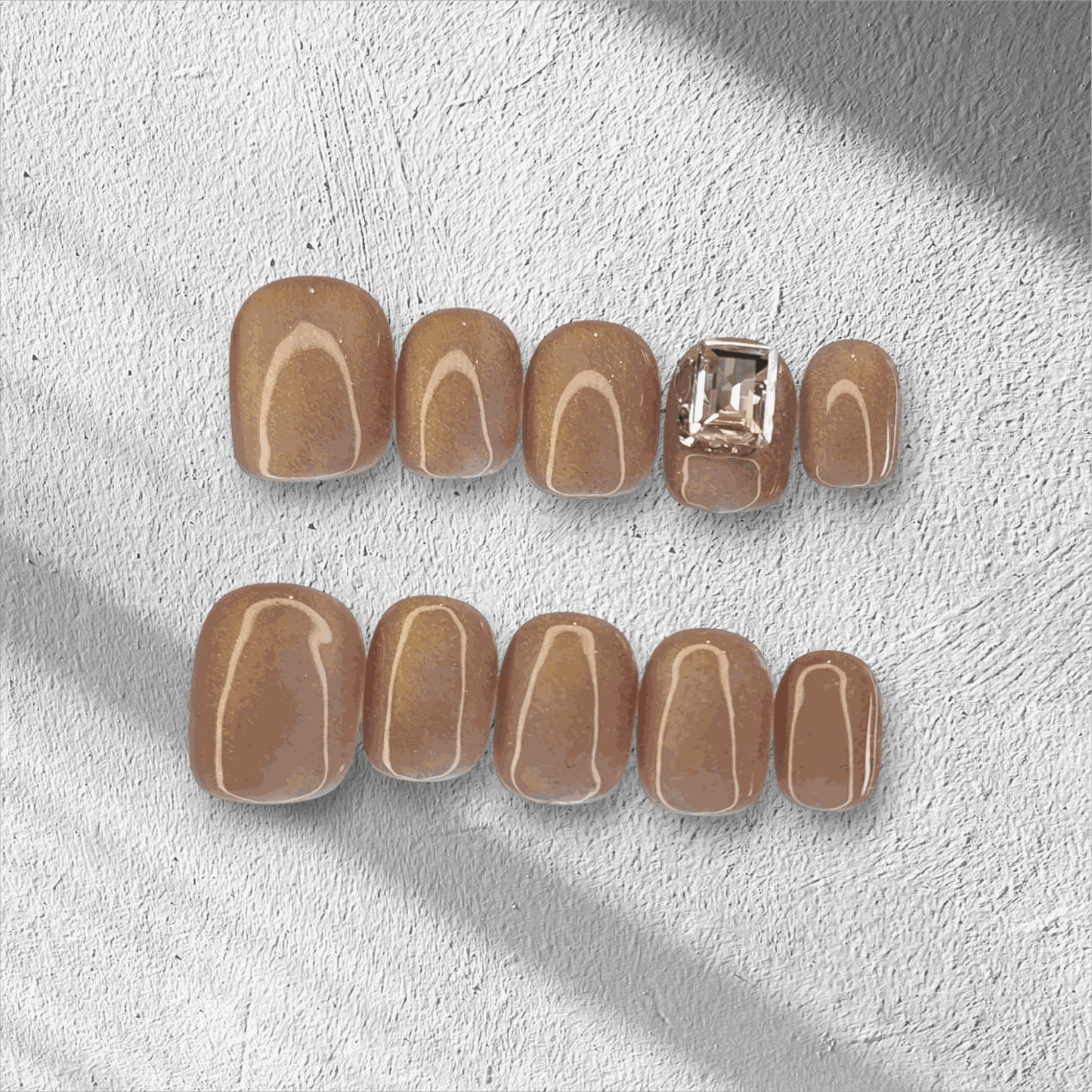 The Bushra press-on nail set in a short squoval shape, displayed in the box.