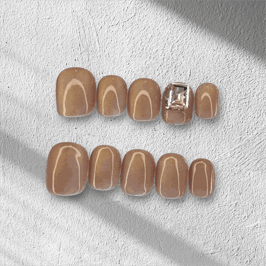 The Bushra press-on nail set in a short squoval shape, displayed in the box.