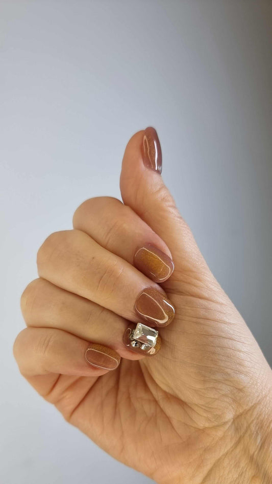 A model's hand wearing the elegant Bushra press-on nails, showcasing the stunning crystal accent nail and the warm nude color.
