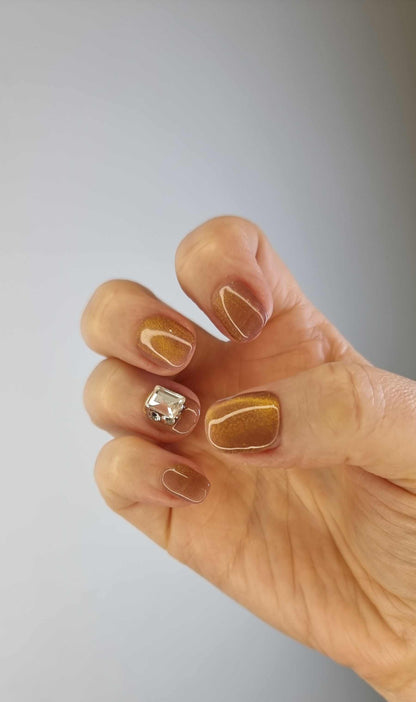 A model's hand wearing the elegant Bushra press-on nails, showcasing the stunning crystal accent nail and the warm nude color.