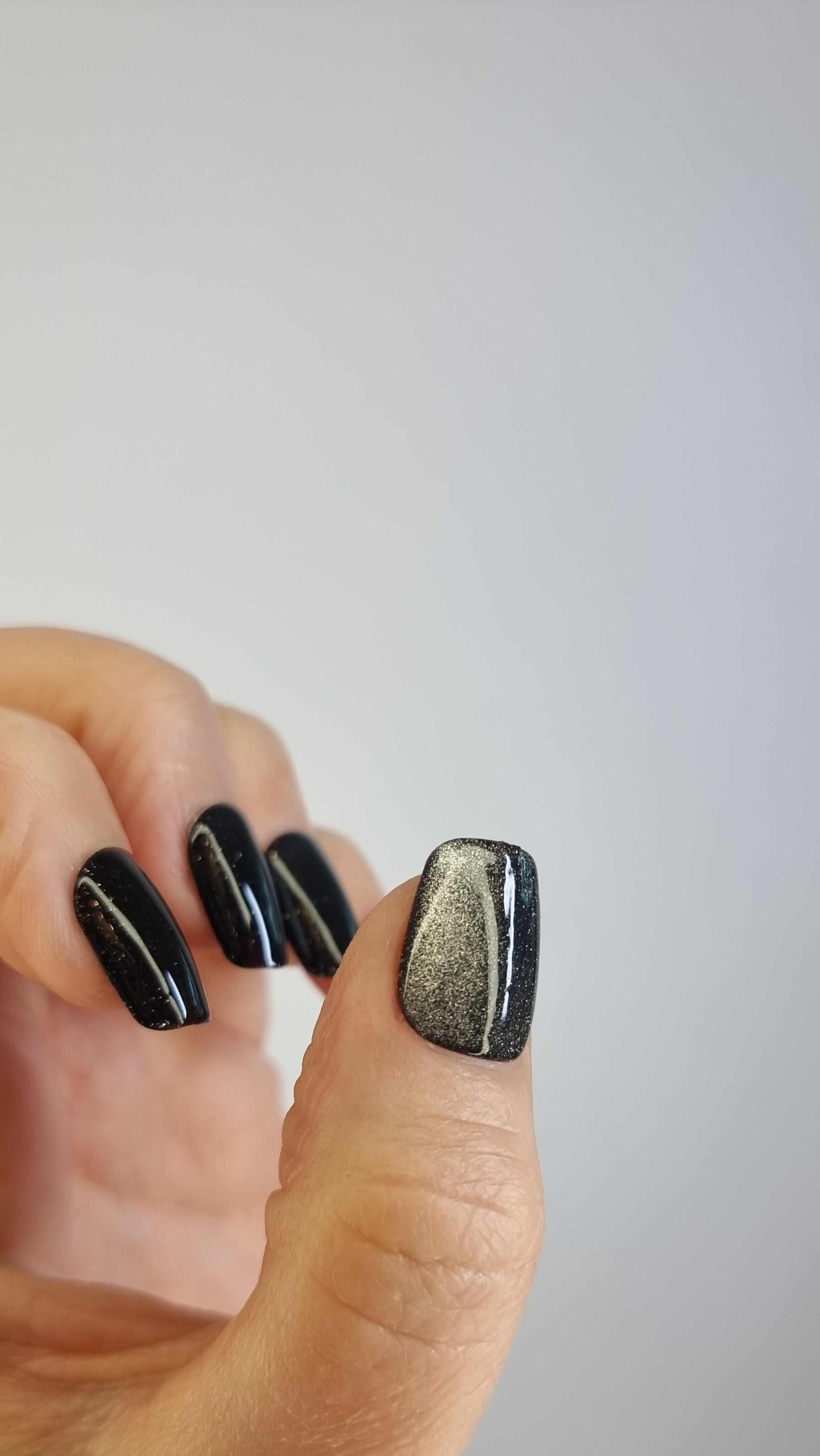 A close-up of the Deira Dusk manicure, highlighting the glossy, glittery finish of the short square press-on nails.