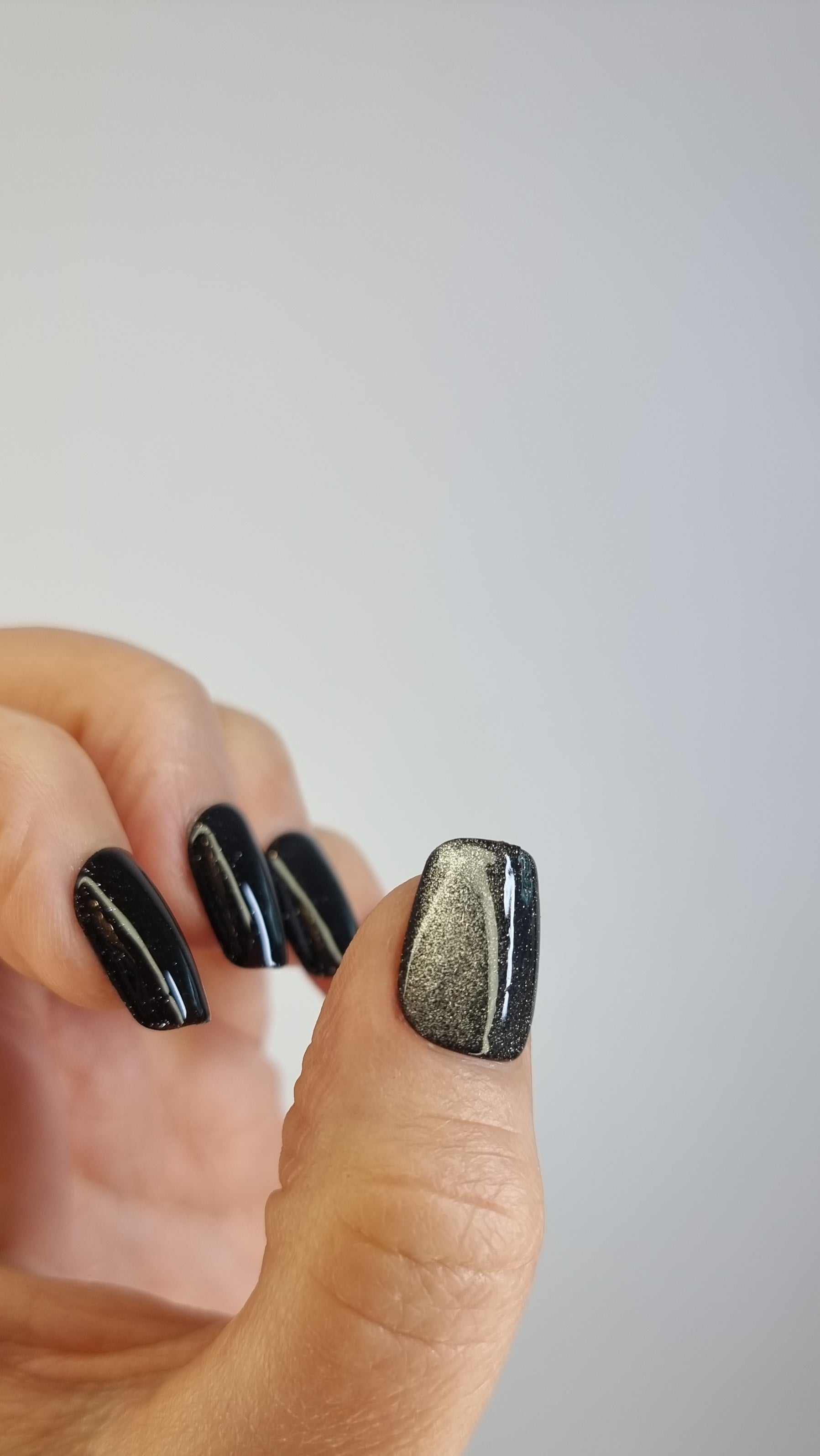 A close-up of the Deira Dusk manicure, highlighting the glossy, glittery finish of the short square press-on nails.