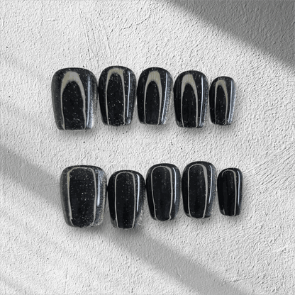 The Deira Dusk press-on nail set in a short square shape, featuring a deep black color with a multi-dimensional glitter finish.