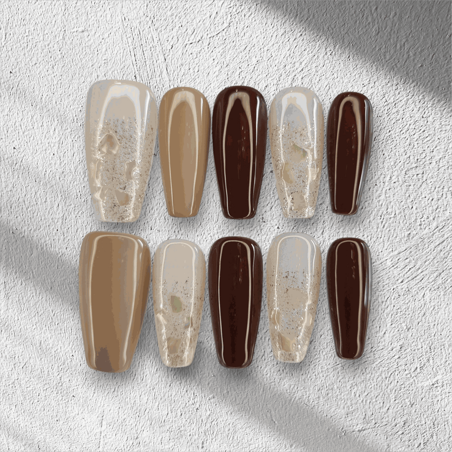 The Desert Crush press-on nail set in a long coffin shape, featuring a mix of brown, nude, and gold glitter nails.