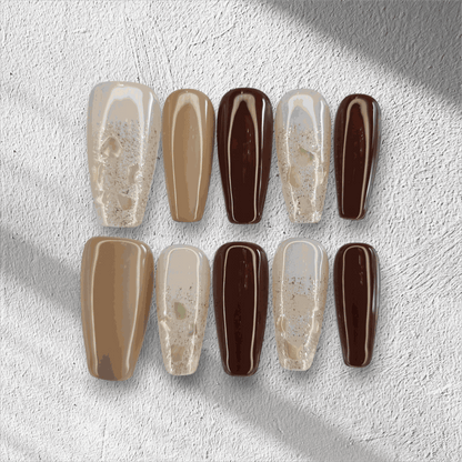 The Desert Crush press-on nail set in a long coffin shape, featuring a mix of brown, nude, and gold glitter nails.