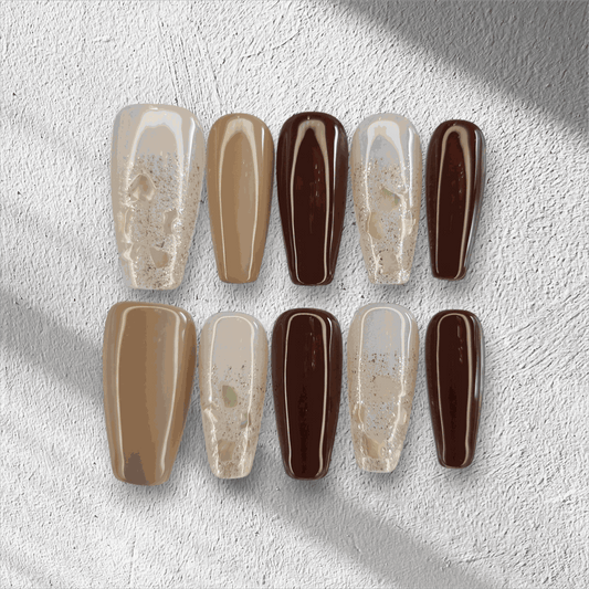 The Desert Crush press-on nail set in a long coffin shape, featuring a mix of brown, nude, and gold glitter nails.